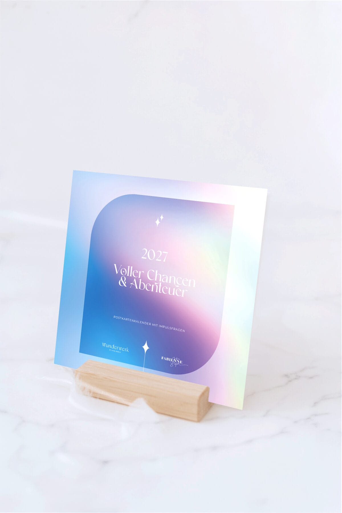 Wunderwerk by Luisa Postkartenkalender 2027 mit buntem Design auf Holzständer.